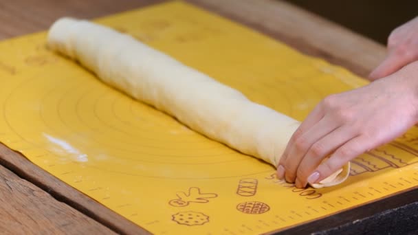 Woman cutting dough for cinnamon rolls on table, closeup — Stock Video