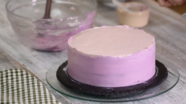 La donna cucina la torta ai mirtilli. La donna spalma una torta con crema su un tavolo di legno bianco . — Video Stock