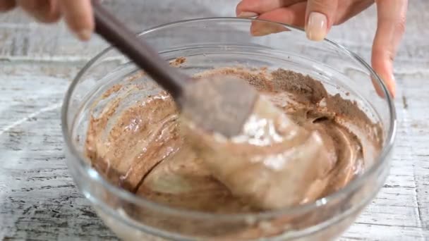 Женская рука перемешивает шоколадное тесто с лопаткой . — стоковое видео