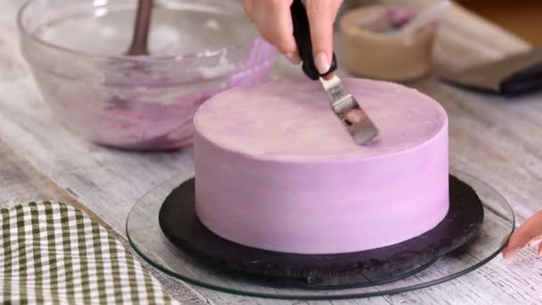 A folyamat díszíti a tortát, lila, krém fedéllel. Cukrász valahol keksz krém péksütemények spatula segítségével. — Stock videók