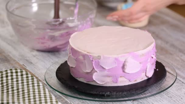 O processo de decorar um bolo com cobertura de creme roxo. Confeiteiro equivale a creme de biscoito usando espátula de pastelaria . — Vídeo de Stock