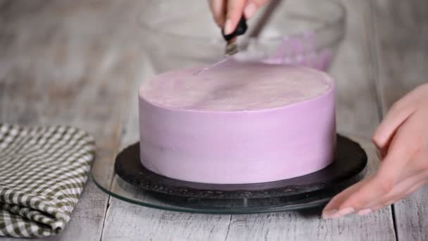 O processo de decorar um bolo com cobertura de creme roxo. Confeiteiro equivale a creme de biscoito usando espátula de pastelaria . — Vídeo de Stock