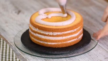 Kadının elinde bir kek üzerine krema sıkma. Lezzetli kek üzerine krema.