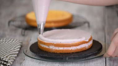 Kadının elinde bir kek üzerine krema sıkma. Lezzetli kek üzerine krema.