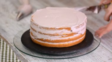 Kadının elinde bir kek üzerine krema sıkma. Lezzetli kek üzerine krema.