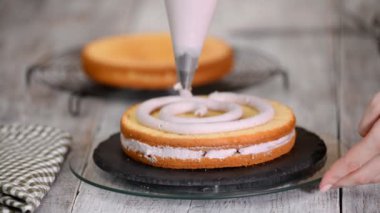 Kadının elinde bir kek üzerine krema sıkma. Lezzetli kek üzerine krema.