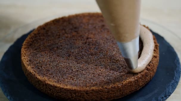 Onherkenbaar vrouwelijke gebak koken persen chocolade crème op smakelijk laag taart in keuken. — Stockvideo