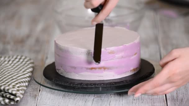 Proces zdobení dort s fialovým krém krytem. Cukrář se rovná sušenka krémem pomocí špachtle těsto. — Stock video