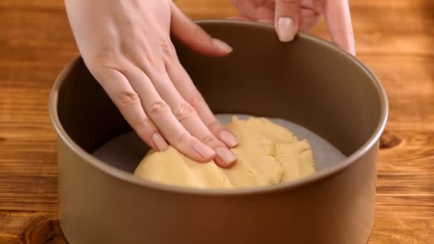 Las manos femeninas emparejan la masa cruda en una bandeja para hornear, utensilios para hornear en el fondo — Vídeos de Stock