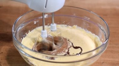 Mutfak masasının arka planında el karıştırıcı ile hamur karıştırma