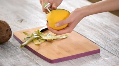 Kadın mutfakta bir mango soyuyor
