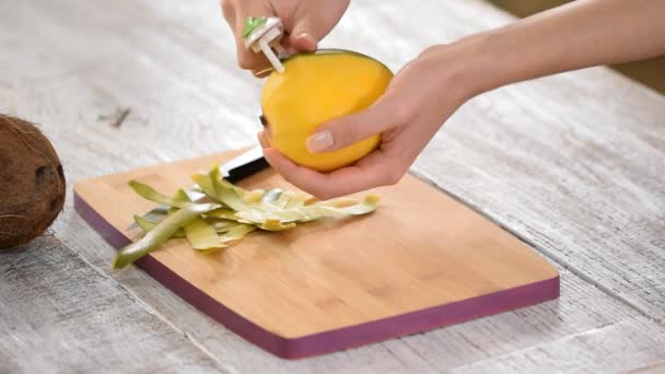 The woman is peeling a mango on the kitchen — Stock Video