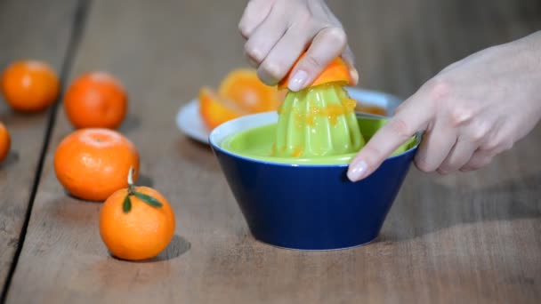 La ragazza spreme il succo da mezzo mandarino . — Video Stock
