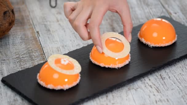 Postre de mousse de mango y coco con recubrimiento de esmalte de espejo naranja. Pastel europeo moderno en el fondo. Pastel de mousse francés cubierto con esmalte naranja . — Vídeos de Stock