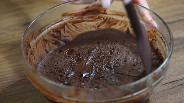 Vrouw roeren heerlijke chocolade crème in kom met spatel op tafel. — Stockvideo