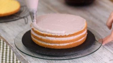 Kadının elinde bir kek üzerine krema sıkma. Lezzetli kek üzerine krema.