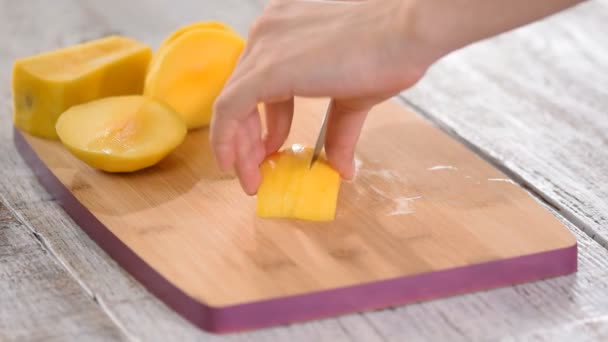 Vrouwelijke chef-koks handen snijden mango op houten snijplank. — Stockvideo