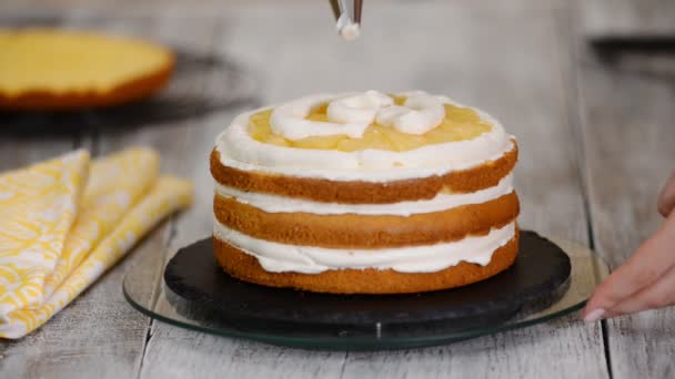 Baker prépare le gâteau avec de la crème. Gros plan du gâteau de lissage Baker à la crème fouettée . — Video