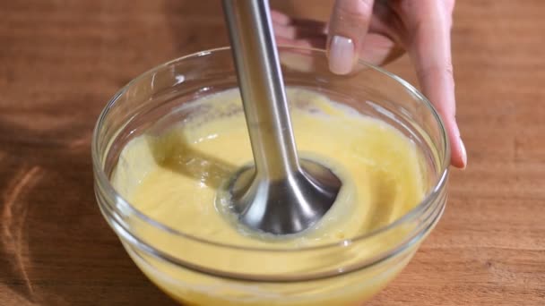 Gros plan fouetter la crème d'orange maison avec un mélangeur dans un bol en verre . — Video