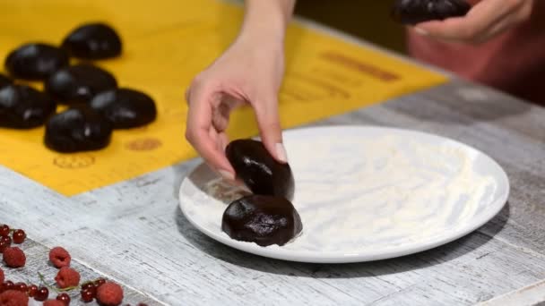 Женщина положила кусочки шоколадного теста на тарелку. Кондитер делает шоколадный пирог . — стоковое видео