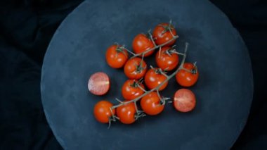 Siyah arka planda kırmızı kiraz domates döndürme. Üst görünüm.