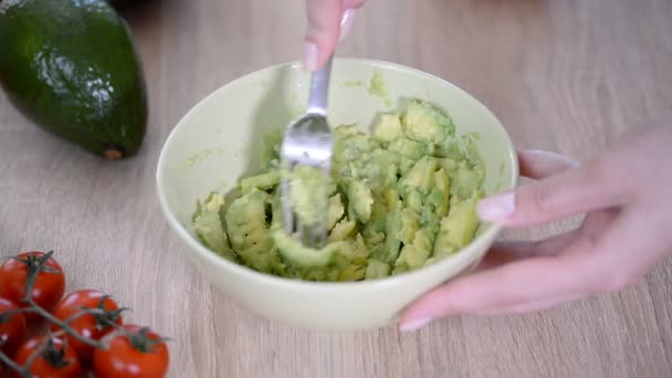 Крупним планом жінки руки затирання авокадо з виделкою в миску — стокове відео