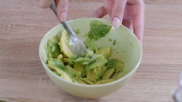 Close-up van vrouw handen Mashing avocado met vork in Bowl. — Stockvideo