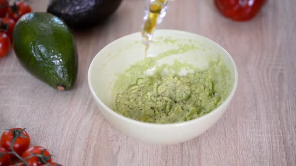 Il cuoco versa l'olio d'oliva in una ciotola di guacamole. Concetto di cibo sano . — Video Stock
