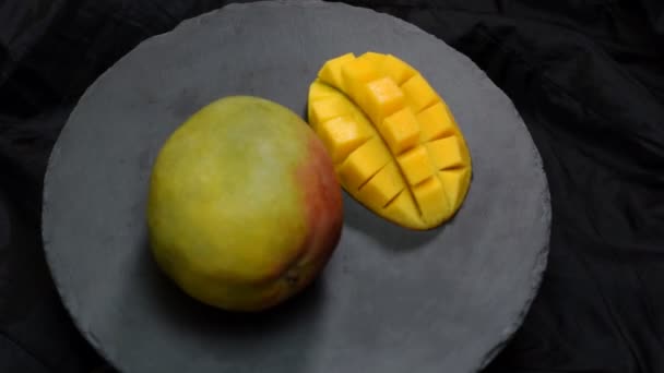 Οργανικά τροπικά φρούτα, κλείστε τις διαφάνειες μάνγκο σε μαύρη πλάκα. — Αρχείο Βίντεο