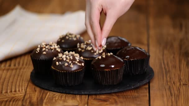 Schokoladenmuffins Mit Zerdrückten Nüssen Auf Holzboden Streuen — Stockvideo