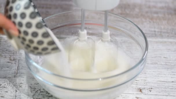 Koki wanita mencambuk putih telur dengan gula dalam mangkuk . — Stok Video