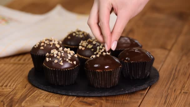 Schokoladenmuffins mit zerdrückten Nüssen auf Holzboden streuen — Stockvideo