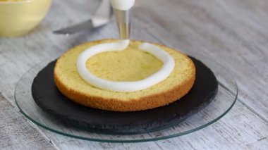 Pudra bisküvi kek üzerine krema sıkar.