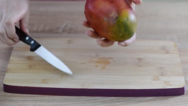 Köchin reicht Scheibe Mango auf Holzschneidebrett. — Stockvideo