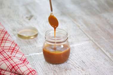 Kaşık kavanoz tablo üzerinde lezzetli karamel sos ile