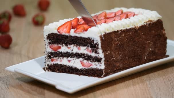Cutting the sweet homemade chocolate cake with strawberry and whipped cream, close up. — Stock Video