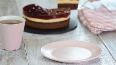 Beyaz arka plan üzerinde, pembe bir tabak üzerinde vanilyalı puding ile Çikolata Lı Kiraz Kek Dilim.