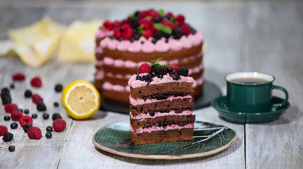 Pièce de gâteau au chocolat avec glaçage et baies fraîches sur fond en bois — Photo