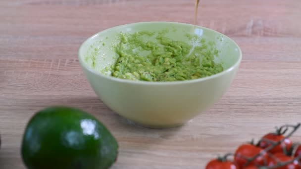 Le cuisinier verse l'huile d'olive dans un bol de guacamole. Concept d'alimentation saine . — Video