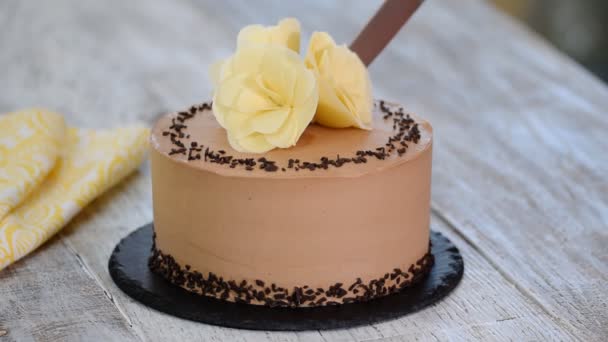 Corte de pastel de chocolate en el plato. Pastel de chocolate decorado flores de chocolate blanco . — Vídeos de Stock