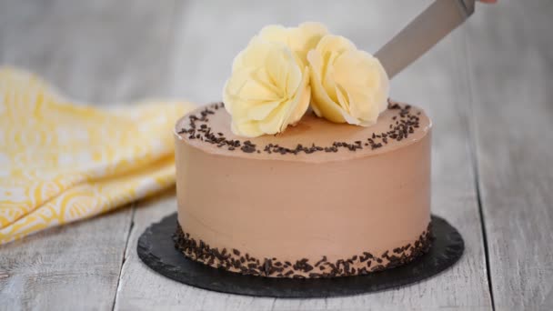 Corte de bolo de chocolate no prato. Bolo de chocolate decorado flores de chocolate branco . — Vídeo de Stock