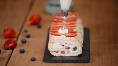 Krema üzerine krema döken bir kadın. Kremalı pasta yapma süreci