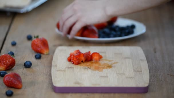 Close up, young girl is cutting fresh strawberries on kitchen — Stock Video