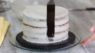 Şekerlemeci mutfakta beyaz krema ile bir pasta yapar