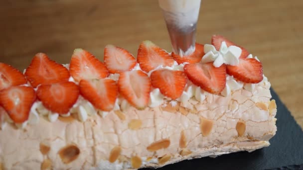 Vrouw met slagroom over meringue-roulade. Proces van het maken van meringue roll. — Stockvideo