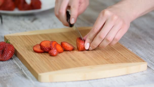 Une femelle coupe des fraises sur une planche de bois. Tranchage de fraises . — Video