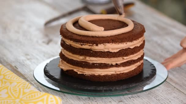 Sahne, die auf Schokoladenkuchen gepresst wird. Sahne auf den Kuchen drücken. — Stockvideo