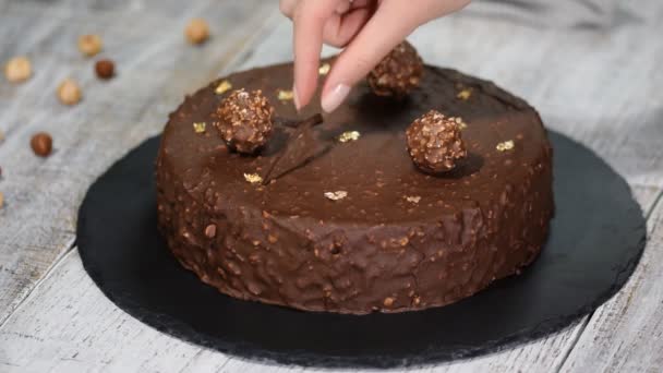 Gâteau aux noisettes au chocolat recouvert de glaçure au chocolat et décoré d'éléments en chocolat, sur fond de bois . — Video