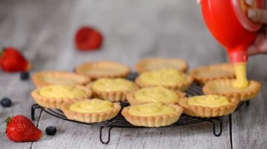 Kız tartlets muhallebi ile doldurur. Pasta. Tatlı tartlets tatlı.