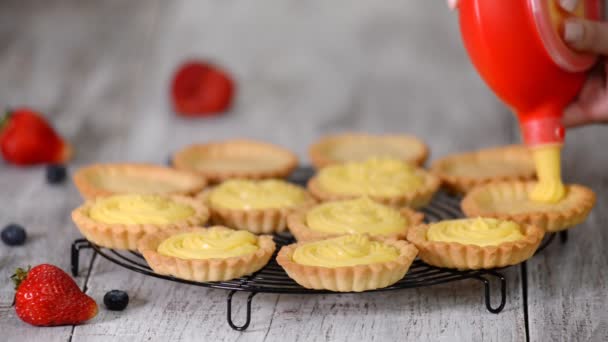 La chica llena tartaletas con natillas. Pastelería. Postre de tartaletas dulces . — Vídeos de Stock